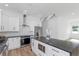 Bright kitchen features white cabinets, black hardware, stainless steel appliances, black countertops, and wood floors at 711 42Nd S Ave, St Petersburg, FL 33705