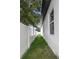 Narrow side yard with green grass between the home's exterior and a white fence at 711 42Nd S Ave, St Petersburg, FL 33705