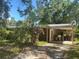 Modest single story home with brick accents, carport, and mature trees in an overgrown lot at 729 41St St, Sarasota, FL 34234