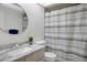 Bright bathroom featuring a round mirror, neutral vanity, and striped shower curtain at 7433 Greystone Dr # 7433, Hudson, FL 34667