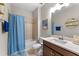 Well-lit bathroom featuring a shower-tub combo, single vanity and a blue shower curtain at 8840 Mugnai St, Riverview, FL 33578