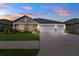 Single-story home featuring a three-car garage and a well-manicured lawn, captured during a vivid sunset at 8840 Mugnai St, Riverview, FL 33578