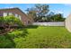 Expansive backyard with verdant lawn, complemented by a sturdy white fence and mature trees at 10101 Paddock Oaks Dr, Riverview, FL 33569