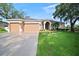 Charming single-story home featuring a well-manicured lawn, a three-car garage, and inviting landscaping at 10101 Paddock Oaks Dr, Riverview, FL 33569