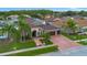 Aerial view displaying a beautifully landscaped home with a three car garage and a brick-paved driveway at 10327 Meadow Crossing Dr, Tampa, FL 33647