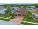 Aerial view showcasing a well-manicured property with lush landscaping, a three car garage, and brick-paved driveway at 10327 Meadow Crossing Dr, Tampa, FL 33647