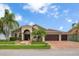 Charming single-Gathering home features a well-manicured lawn, mature palm trees, brick driveway, and a 3-car garage at 10327 Meadow Crossing Dr, Tampa, FL 33647