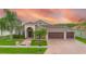 Exterior elevation features an oversized three car garage, brick paver driveway, and arched entryway at 10327 Meadow Crossing Dr, Tampa, FL 33647