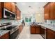 Well-lit kitchen with granite countertops, stainless appliances, and wood cabinetry at 11220 Paradise Pointe Way, New Port Richey, FL 34654
