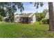 Well-maintained backyard featuring lush green grass, mature trees, and a screened lanai at 12529 Knollbrook Ln, Hudson, FL 34669