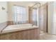 Bathroom featuring a soaking tub with tile surround, shower and window with light filtering blinds at 12631 Chenwood Ave, Hudson, FL 34669