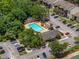 Aerial view of the neighborhood community pool surrounded by trees, parking, and apartment buildings at 13285 Arbor Pointe Cir # 202, Tampa, FL 33617