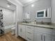 Bright bathroom with white cabinets, granite counters, wood-look flooring, and a tub with marble-look tile surround at 13285 Arbor Pointe Cir # 202, Tampa, FL 33617