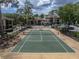 View of a community tennis court with a fence, surrounding landscaping, and community buildings in the background at 13285 Arbor Pointe Cir # 202, Tampa, FL 33617