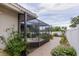 Relaxing backyard featuring a screened-in hot tub, brick patio, and mature tropical foliage at 1441 S Hercules Ave, Clearwater, FL 33764