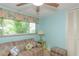 A bedroom with blue walls, ceiling fan, couch, ottoman, and a window at 1441 S Hercules Ave, Clearwater, FL 33764