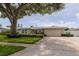 Exterior of the home featuring a well-maintained lawn, large tree, and attached garage at 1441 S Hercules Ave, Clearwater, FL 33764
