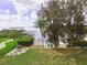 Expansive backyard with lush greenery, dock with seating, a fire pit, and access to the water at 1626 Sea Breeze Dr, Tarpon Springs, FL 34689