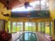 Unique indoor pool room with tile flooring, large windows, and tropical-themed decor for year-round enjoyment at 1626 Sea Breeze Dr, Tarpon Springs, FL 34689