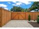 The backyard has a wooden fence with white stones, a gate, and lush greenery at 1707 Solon Ave, Dunedin, FL 34698