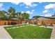 A large manicured backyard with green grass, a grill station, and shaded seating areas at 1707 Solon Ave, Dunedin, FL 34698
