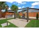 Well-manicured backyard featuring hanging egg chairs, grill area, and lush landscaping at 1707 Solon Ave, Dunedin, FL 34698