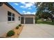 Well-maintained home featuring a concrete driveway leading to a gray garage door, and manicured landscaping at 1707 Solon Ave, Dunedin, FL 34698