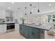 Bright kitchen features modern stainless steel appliances, island with bar, and white cabinets at 1707 Solon Ave, Dunedin, FL 34698