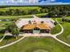 Aerial shot of a clubhouse, parking lot, and surrounding green landscape including a pond and road at 18168 Clearview Dr, Brooksville, FL 34604