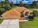 Aerial view of a single-story home with a three-car garage, lush landscaping, and a well-manicured lawn at 18168 Clearview Dr, Brooksville, FL 34604