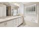 Bathroom boasting dual sinks, a soaking tub, and a glass block window for added privacy at 18203 Tivoli Ln, Lutz, FL 33558