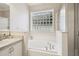 Clean and bright bathroom with a soaking tub, glass block window, and a glass-enclosed shower at 18203 Tivoli Ln, Lutz, FL 33558