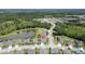 Drone view showcasing a home near a pond in a neighborhood surrounded by trees at 18527 Cortes Creek Blvd, Spring Hill, FL 34610