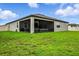 Home showcasing a screened-in lanai overlooking the spacious backyard with lush green grass at 18527 Cortes Creek Blvd, Spring Hill, FL 34610