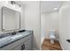 Bathroom featuring gray vanity, marble countertop, mirror, and toilet with wood-look floor at 19275 Wildwood Dr, Brooksville, FL 34601