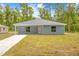 Inviting single-story home with light blue siding, a modern roof, and a well-manicured front lawn at 19275 Wildwood Dr, Brooksville, FL 34601