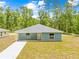 Charming single-story home featuring light blue siding and a well-manicured lawn at 19275 Wildwood Dr, Brooksville, FL 34601