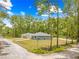 Street view showcasing the exterior of the home, surrounded by trees and green grass at 19275 Wildwood Dr, Brooksville, FL 34601