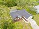 Aerial view of the home featuring a spacious driveway, a screened pool, and lush surroundings at 2141 Coachman Rd, Spring Hill, FL 34608