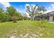 Lush backyard with mature trees and a screened pool providing a private outdoor retreat at 2141 Coachman Rd, Spring Hill, FL 34608