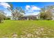 Expansive backyard featuring a screened-in pool and mature trees, perfect for outdoor activities at 2141 Coachman Rd, Spring Hill, FL 34608
