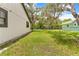 Side yard view with ample green space and partial view of neighboring home and mature trees at 2141 Coachman Rd, Spring Hill, FL 34608