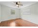 Comfortable bedroom with hardwood floors, natural light from two windows, and a ceiling fan at 2141 Coachman Rd, Spring Hill, FL 34608
