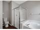 White soaking tub with a glass shower enclosure and wood look flooring at 22824 Marsh Wren Dr, Land O Lakes, FL 34639