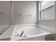 Close-up of a white soaking tub with chrome fixtures and a tiled surround at 22824 Marsh Wren Dr, Land O Lakes, FL 34639