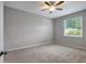 Bright bedroom features plush carpeting, a ceiling fan, and a sunlit window at 22824 Marsh Wren Dr, Land O Lakes, FL 34639
