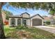 Charming home exterior with a well-kept lawn, two-car garage and lush greenery, shaded by a mature tree at 22824 Marsh Wren Dr, Land O Lakes, FL 34639