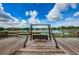 Wooden deck with black swing, leading over lush, green grass toward a large lake at 2455 Anthony Ave, Clearwater, FL 33759