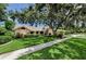 Charming single-story home with lush landscaping and a concrete walkway underneath a large tree at 2455 Anthony Ave, Clearwater, FL 33759