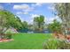 Tranquil backyard featuring a serene lake view, lush greenery, and well-maintained lawn at 3026 Cedaridge Dr, Tampa, FL 33618